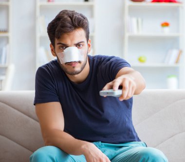 Genç adam estetik cerrahi burnundan sonra evde iyileşiyor.