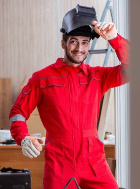 Kaynak tabancası elektrot ve kask takan genç bir tamirci.