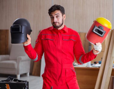 Kaynak tabancası elektrot ve kask takan genç bir tamirci.