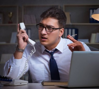 İş adamı telefonda konuşuyor ve ofiste sigara içiyor.