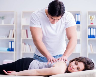 Genç doktor kayropraktik uzmanı kadın hastaya masaj yapıyor.
