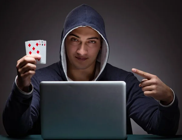 Young man wearing a hoodie sitting in front of a laptop computer — Stock Photo, Image