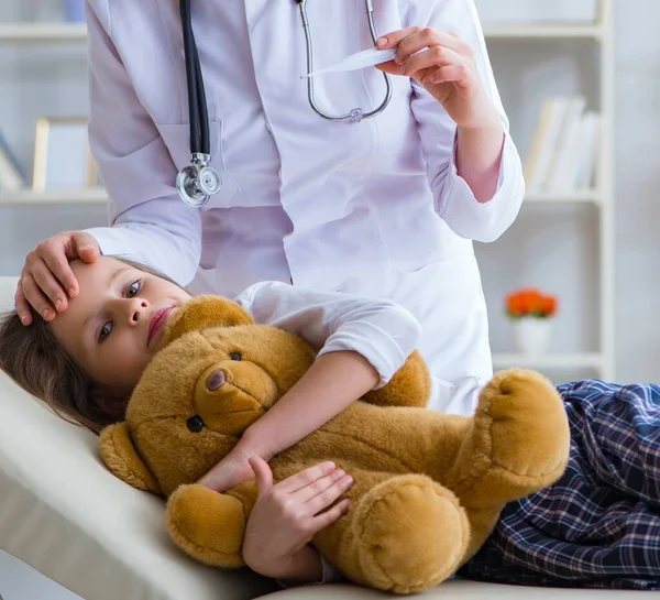 Mujer médico femenino examinando poco linda chica con juguete oso —  Fotos de Stock