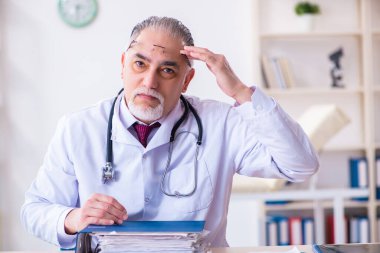 Klinikte çalışan yaşlı erkek doktor.