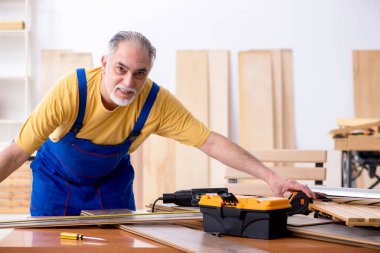 Yaşlı erkek marangoz atölyede çalışıyor.