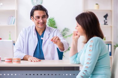 Orta yaşlı bir kadın, erkek doktor stomatoloğu ziyaret ediyor.