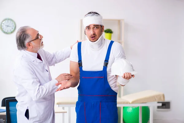 Jovem empreiteiro visitando médico velho — Fotografia de Stock