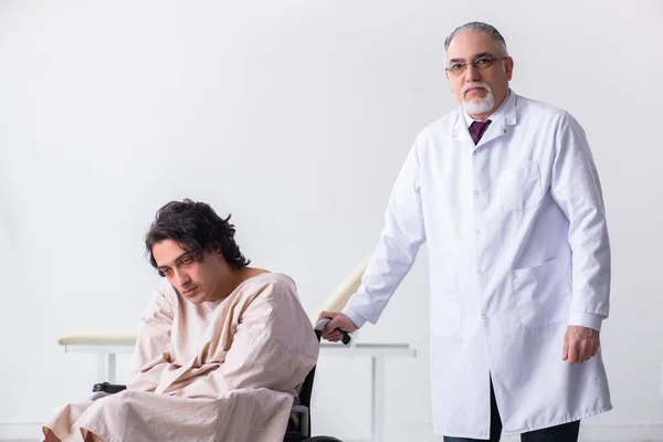 Old male doctor psychiatrist and patient in wheel-chair