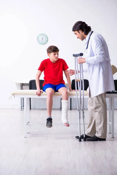 Beengewonde jongen op bezoek bij jonge dokter traumatoloog — Stockfoto