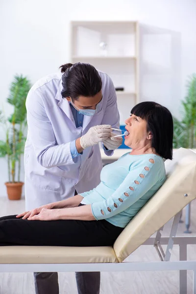 Mulher velha visitando jovem médico dentista — Fotografia de Stock