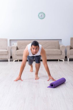 Genç adam evde antrenman ve egzersiz yapıyor.