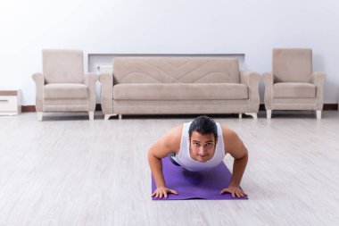 Genç adam evde antrenman ve egzersiz yapıyor.