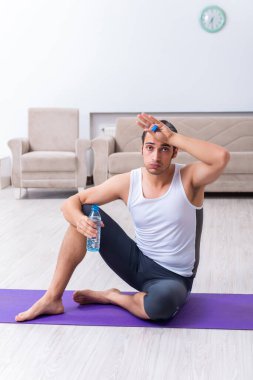 Genç adam evde antrenman ve egzersiz yapıyor.