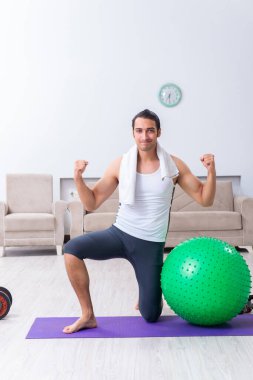Genç adam evde antrenman ve egzersiz yapıyor.