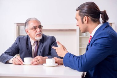 İki işadamı ofiste iş konuşuyor.