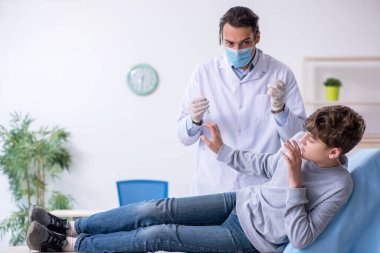 Genç çocuk hastanede doktoru ziyaret ediyor.
