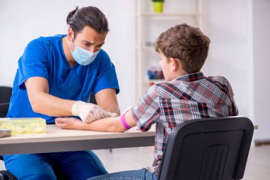 Genç çocuk hastanede doktoru ziyaret ediyor.
