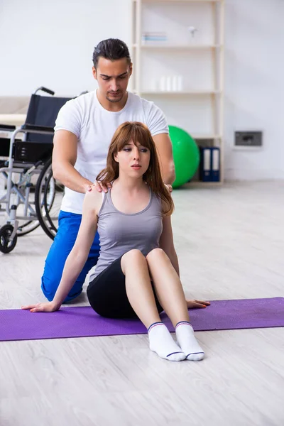 Fisioterapista maschile che fa esercizi con donna ferita sul pavimento — Foto Stock