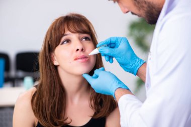 Genç bir kadın erkek doktor dermatoloğunu ziyaret ediyor.