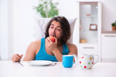 Genç adam evde uyanıyor.