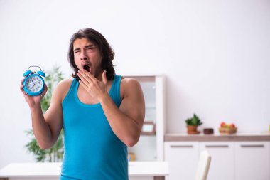 Genç adam evde uyanıyor.