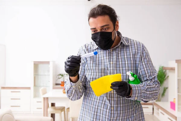 若い男性の請負業者は、コロナウイルスの概念で家を掃除 — ストック写真