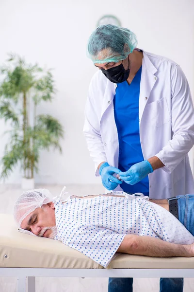 Old man visiting young male intern doctor — Stock Photo, Image