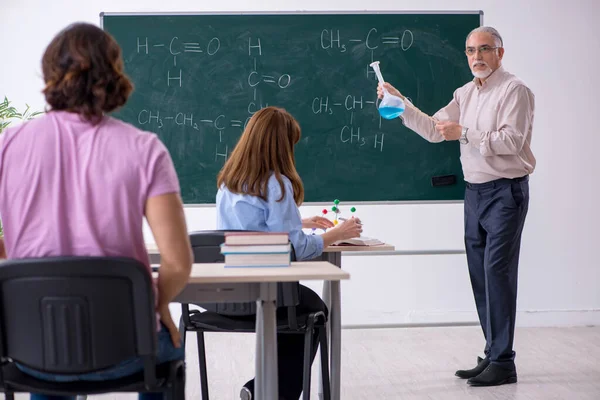 Oude scheikundeleraar en twee leerlingen in de klas — Stockfoto