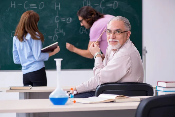 Régi kémikus tanár és két diák az osztályteremben. — Stock Fotó