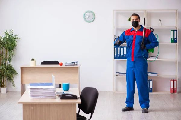 Contratista masculino joven desinfectando oficina —  Fotos de Stock