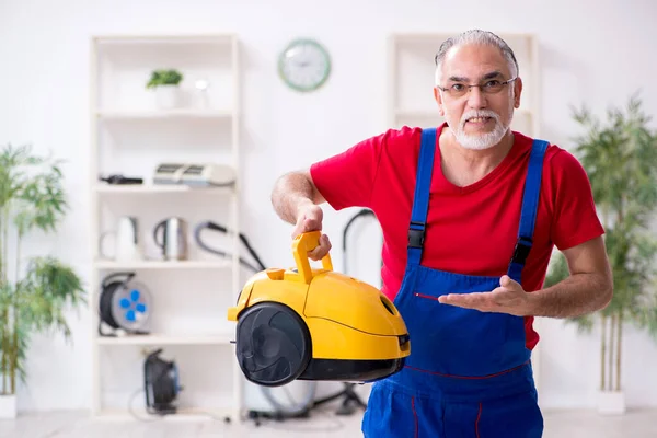 Evde elektrik süpürgesi tamir eden yaşlı bir erkek müteahhit. — Stok fotoğraf