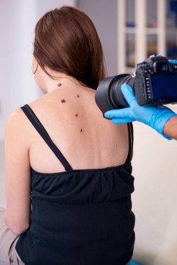 Genç bir kadın erkek doktor dermatoloğunu ziyaret ediyor.