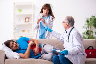 İki doktor hasta bir genci ziyaret ediyor.