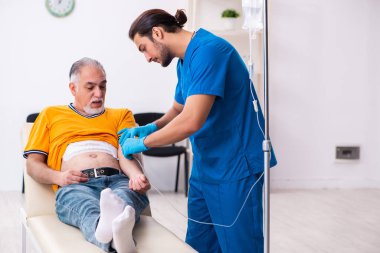 Yaşlı adam genç erkek doktoru ziyaret ediyor.