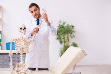 İskeleti olan genç erkek doktor.