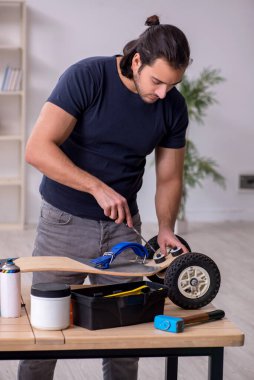 Kaykay tamir eden genç bir erkek tamirci.