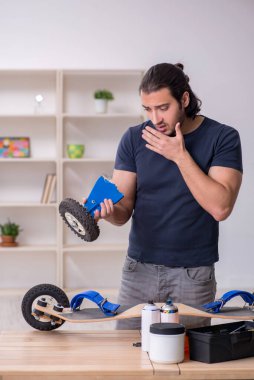 Kaykay tamir eden genç bir erkek tamirci.