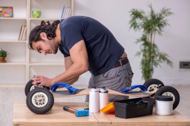 Kaykay tamir eden genç bir erkek tamirci.