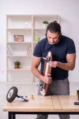 Kaykay tamir eden genç bir erkek tamirci.