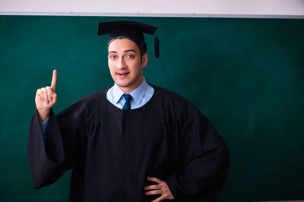 Jovem do sexo masculino graduado na frente da placa — Fotografia de Stock