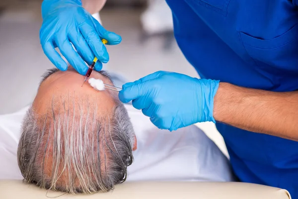 Vieil homme visitant jeune médecin masculin en conce de transplantation de cheveux — Photo