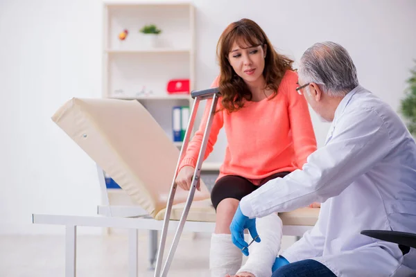 Genç bacak yaralı kadın yaşlı doktor travmatoloğu ziyaret ediyor. — Stok fotoğraf