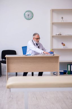 Klinikte çalışan yaşlı erkek doktor.