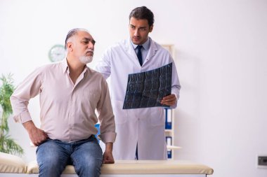 Yaşlı hasta genç erkek doktoru ziyaret ediyor.