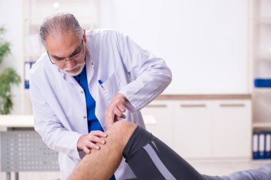 Genç erkek hasta yaşlı doktor travmatoloğu ziyaret ediyor.