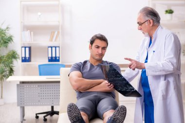 Genç erkek sporcu yaşlı doktor radyolojisti ziyaret ediyor.