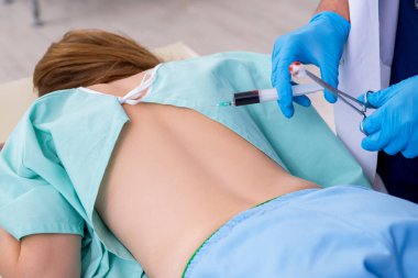 Genç sırtı yaralı kadın, erkek doktor masörünü ziyaret ediyor.