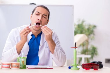 Klinikte çalışan genç erkek dişçi.
