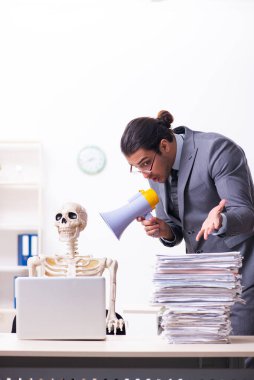 Genç erkek çalışan ve iskelet ofiste.