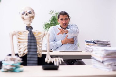 Genç erkek çalışan ve iskelet ofiste.